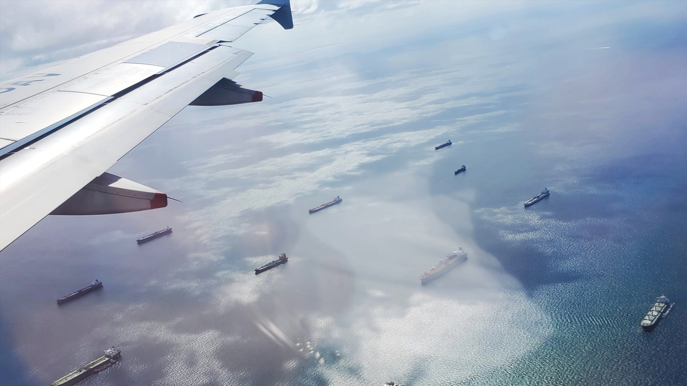 Many cargo ships in the ocean captured from an airplane window.