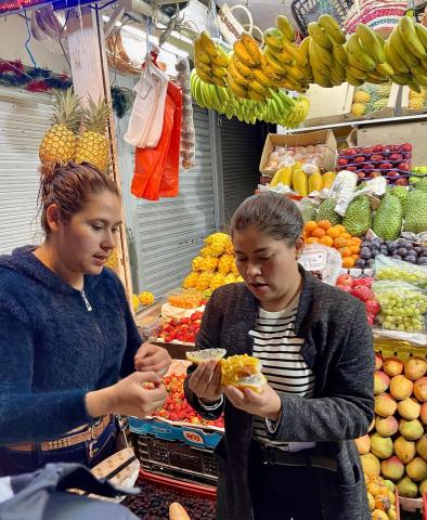 Two women discuss dragon fruit at a Bogota market.