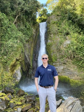 A team member in front of a waterfall.