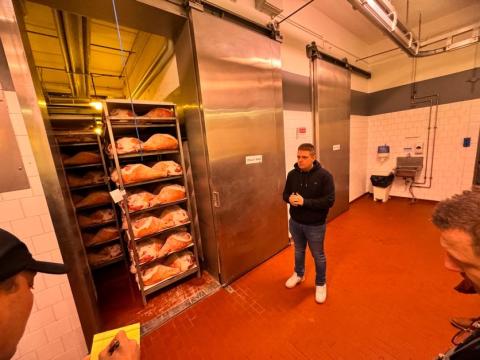 The ham company owner stands near curing hams.