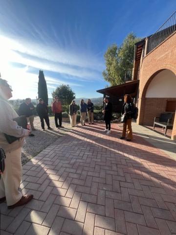 The LEAD class listens to a speaker on a patio outside a vineyard.