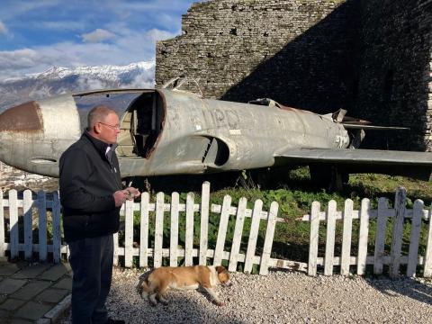 Joe Ruskamp is pictured taking in the castle. The plane behind him is an American plane that landed in the area during the communist time. The dog laying down is a local, free-range dog. 